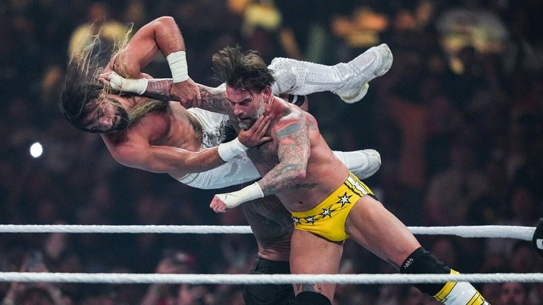 CM Punk hits Seth Rollins with a strike in the middle of the ring during their match with Roman Reigns at WrestleMania 41.