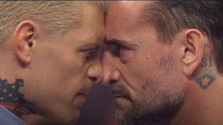 Cody Rhodes and CM Punk scowl at each other, with mere inches between their faces.