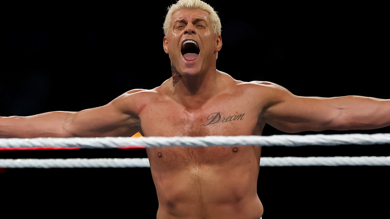 Cody Rhodes outstretches his arms and shouts.