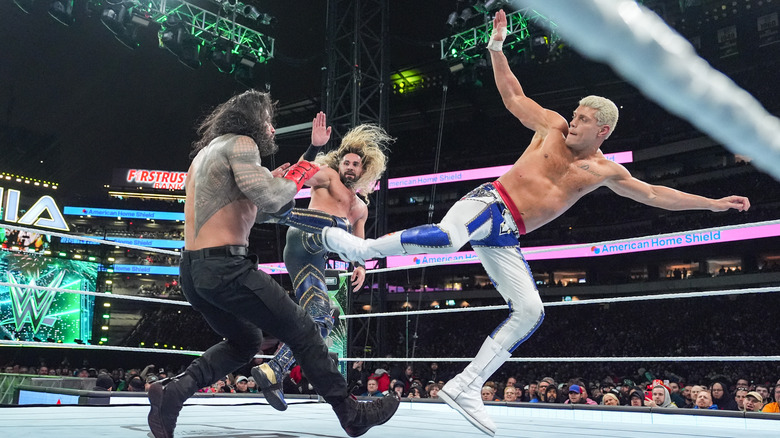 Cody Rhodes and Seth Rollins superkicking Roman Reigns