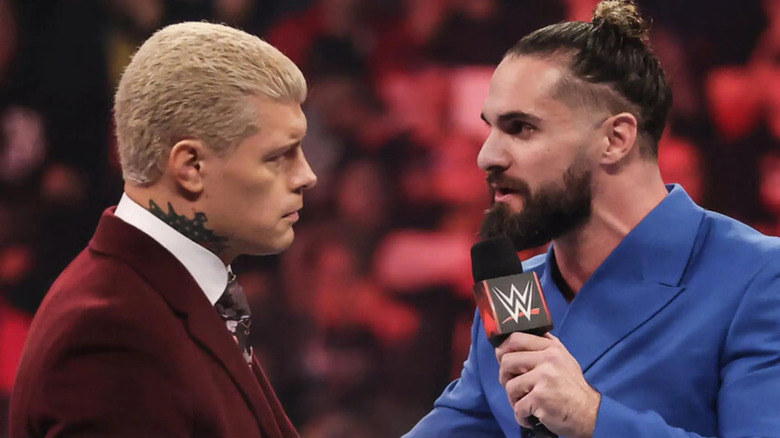 Seth Rollins speaks to Cody Rhodes with a microphone in hand.