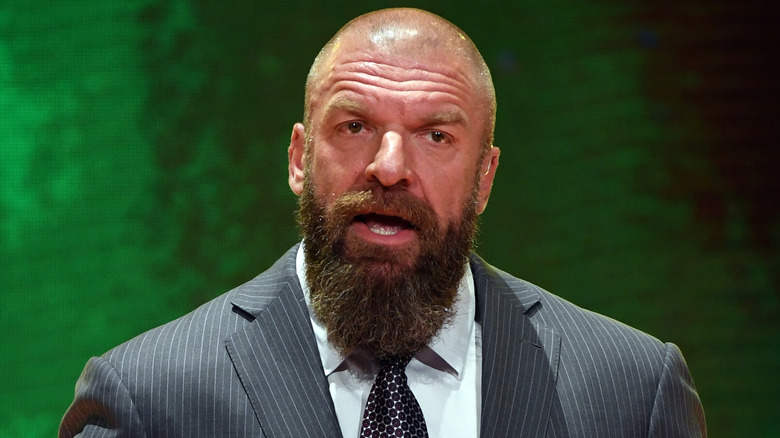 Paul Levesque standing in front of a green background