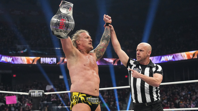 A referee raises the hand of Chris Jericho, who holds the ROH World Championship, in the middle of the ring at AEW Dynasty.