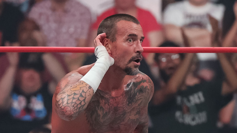 CM Punk cupping his right ear with his right hand