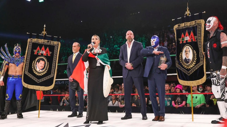 WWE and AAA officials, as well as AAA wrestlers, stand in the ring and honor those departed as a singer performs ahead of WWE x AAA Worlds Collide 2025.