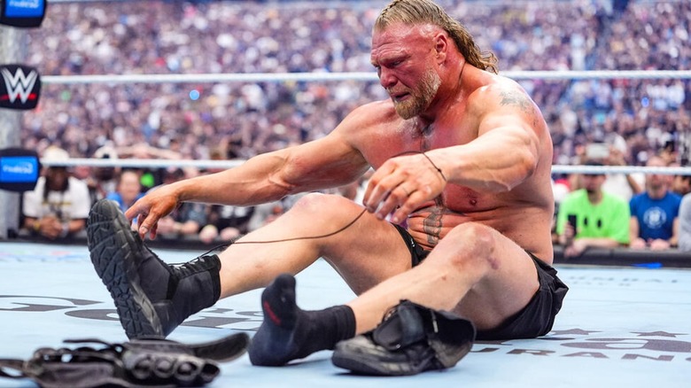 Brock Lesnar unlacing his shoes after taking his gloves off in the middle of the ring after losing to Oba Femi at WrestleMania 42.