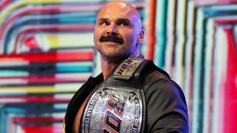 Dax Harwood of FTR smiles with the ROH World Tag Team Championship ahead of a match.
