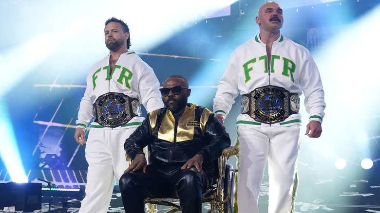 FTR's Cash Wheeler and Dax Harwood making their way to the ring with a wheelchair-bound Stokely Hathaway during their reign as AEW World Tag Team Champions.