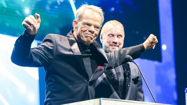Lex Luger standing up during his WWE Hall of Fame 2025 induction, with Diamond Dallas Page at his side.