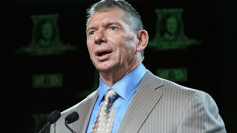 Vince McMahon speaks in front of two conference microphones.