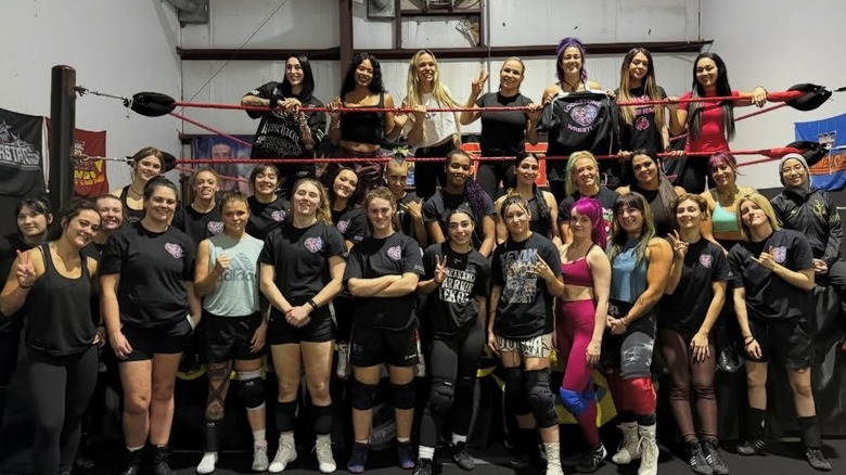 Bayley, along with several guest coaches, all pose with the 20 independent female wrestlers who participated in the Grand Slam Champion's first-ever Lodestone event