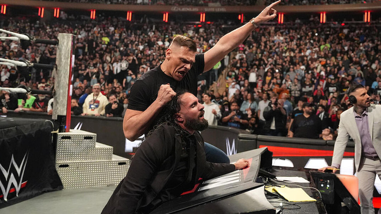 GUNTHER holds Seth Rollins up by the hair while pointing at the WrestleMania sign