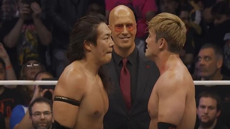 Don Callis stands in between Konosuke Takeshita and Kazuchika Okada in the ring as they stare each other down during an episode of AEW programming.