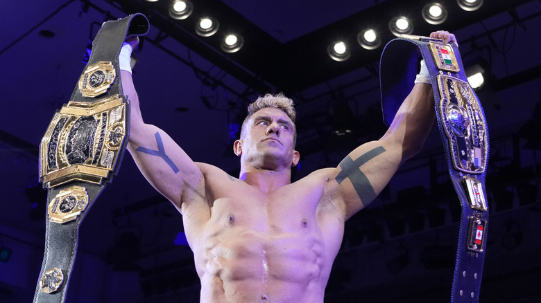 EC3 poses with two titles, including the NWA World's Heavyweight Championship at an All Japan Pro Wrestling event