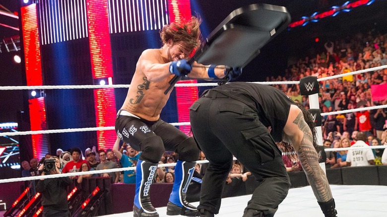 AJ Styles blasts Roman Reigns with a chair.