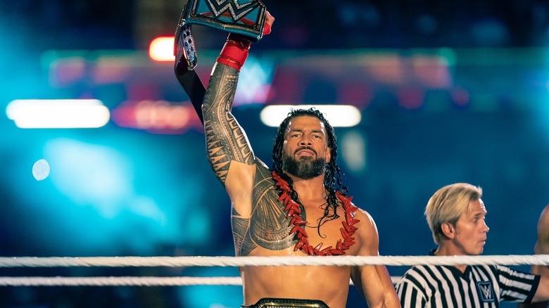 Roman Reigns holds his title belt high