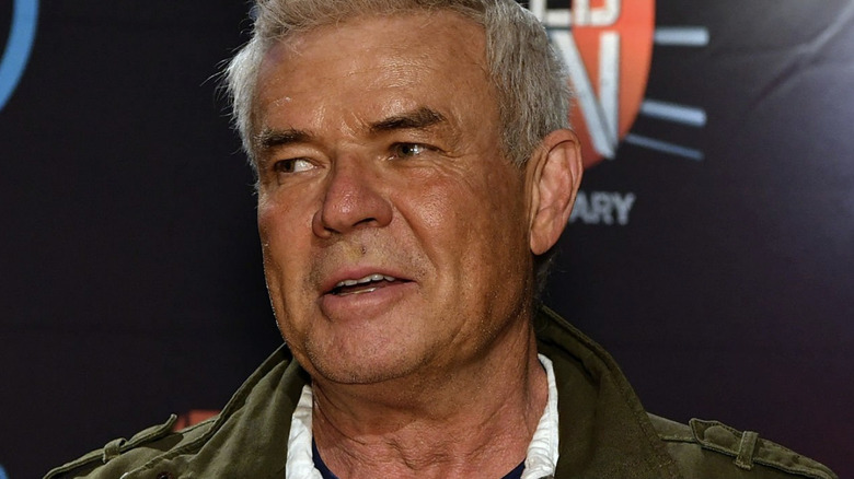 Eric Bischoff appears in a dark green jacket and white collared shirt on an episode of 