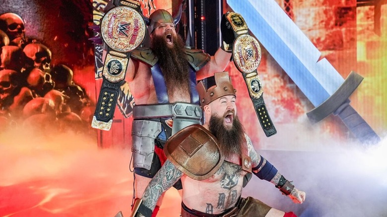 The War Raiders, Erik and Ivar, pose on the stage, WWE World Tag Team Championships in hand, during an entrance ahead of a match.