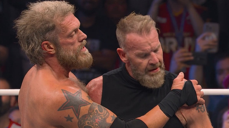 Cope clasps Christian Cage's shoulder in a side embrace.
