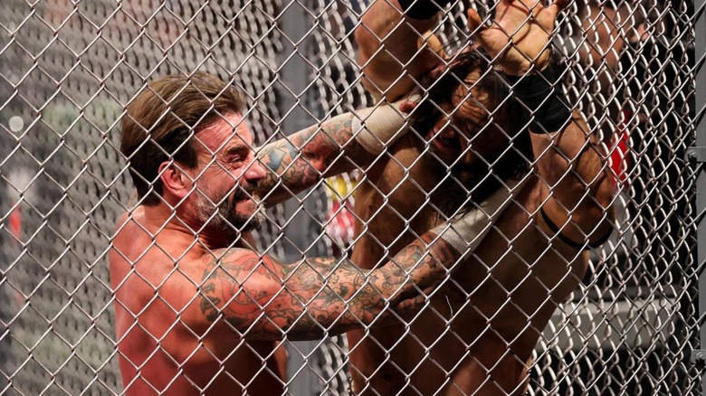 CM Punk scrapes Drew McIntyre's face against the cage during the Hell in a Cell Match in October 2024.