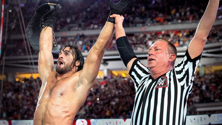 Mike Chioda levanta el brazo de Seth Rollins después de cobrar el maletín de Money in the Bank para ganar el Campeonato de la WWE en WrestleMania.