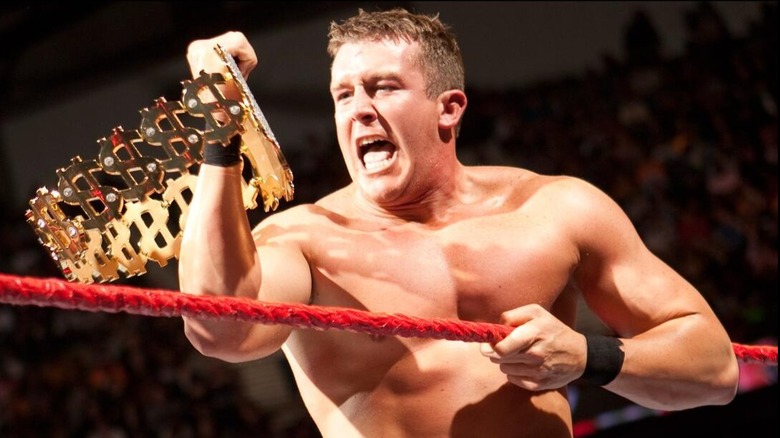 Ted DiBiase Jr. holds his dad's Million Dollar Championship up in the ring