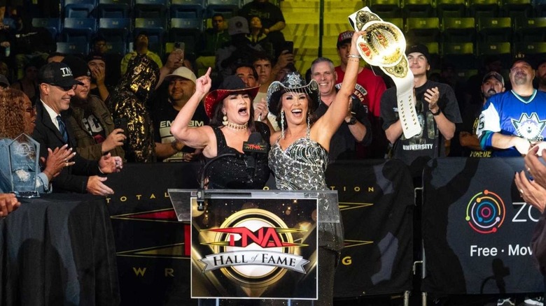 Lisa Marie Varon hugs Mickie James, who holds up the Knockouts Championship, during the 2025 TNA Hall of Fame induction ceremony at Bound for Glory.