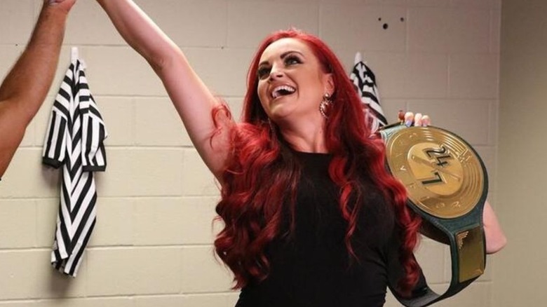 A referee holds up the hand of Maria Kanellis after she defeated her husband to become WWE 24/6