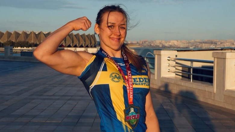 Ellen Akesson poses with a medal around her neck, flexing while announcing she's a world champion, in a photo posted to her X account.