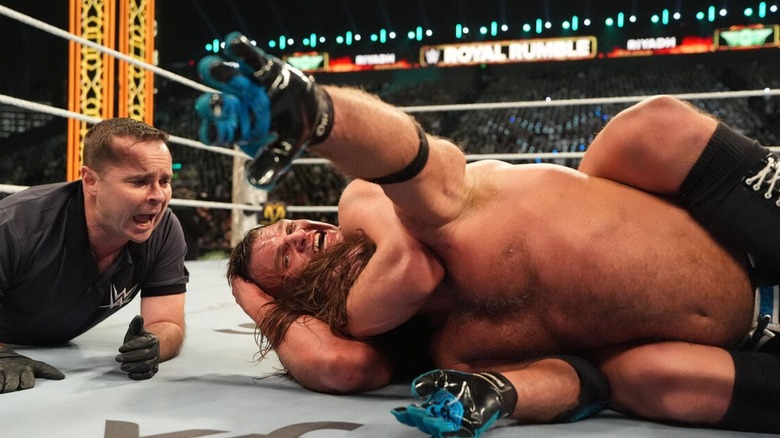 GUNTHER puts AJ Styles in a sleeper hold, as Styles reaches for the ropes during their match, Styles' last, at the 2026 Royal Rumble.