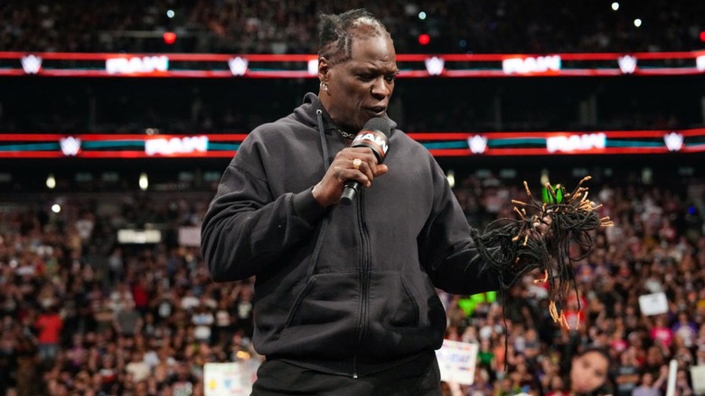 R-Truth cuts a promo, while looking the locs he just cut off his head, while standing on the commentary desk during an episode of "WWE Raw."