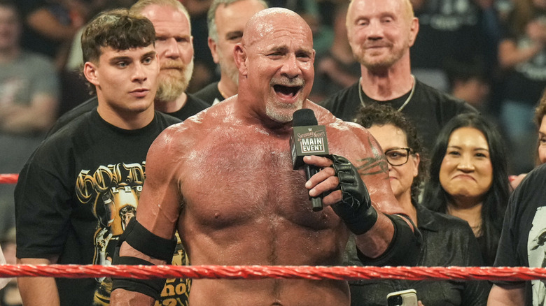 Goldberg standing in the ring with his son Gage and others