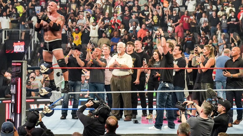 Goldberg claps at the audience following his farewell match, with his family and friends accompanying him in the ring