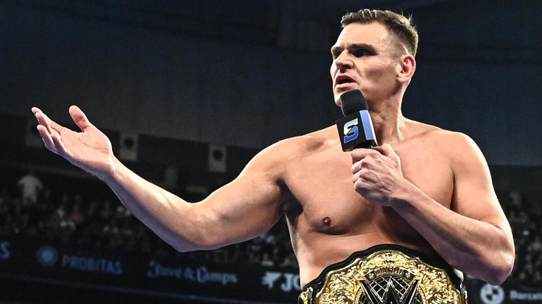 GUNTHER speaks into the microphone whilst bearing the WWE World Heavyweight Championship.