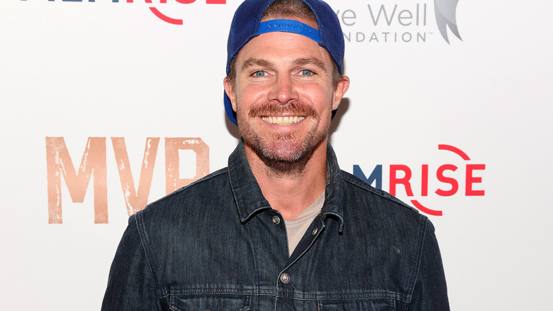 Stephen Amell is very happy with his baseball cap look on the red carpet