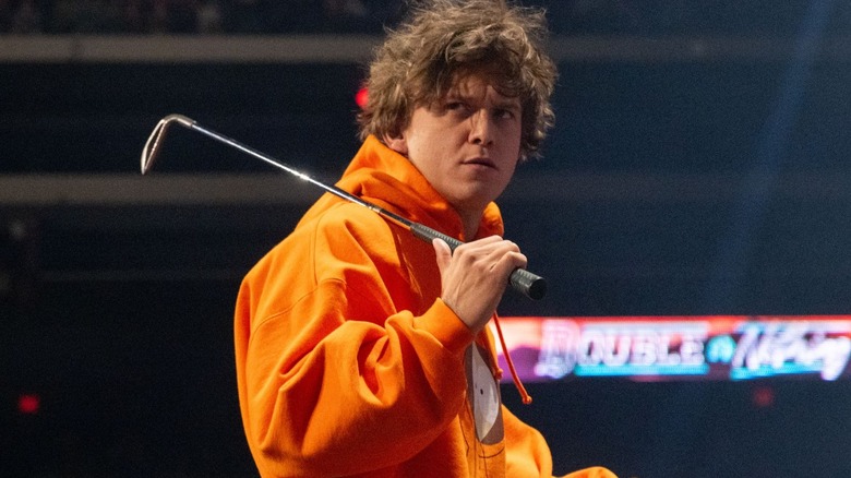 Hook looks to the ring with a scowl on his face, a golf club slung over his shoulder, during the Anarchy in the Arena match at AEW Double or Nothing.