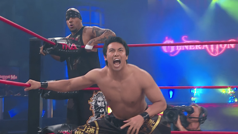 Kazuchika Okada crouching in a TNA ring with tag team partner Homicide on the outside