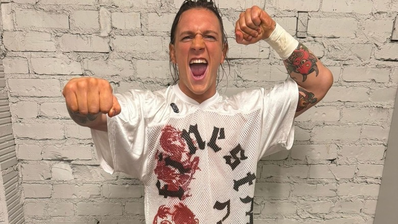 Independent star Marcus Mathers poses backstage in a t-shirt and his ring gear ahead of a match, in a photo posted to his X account.