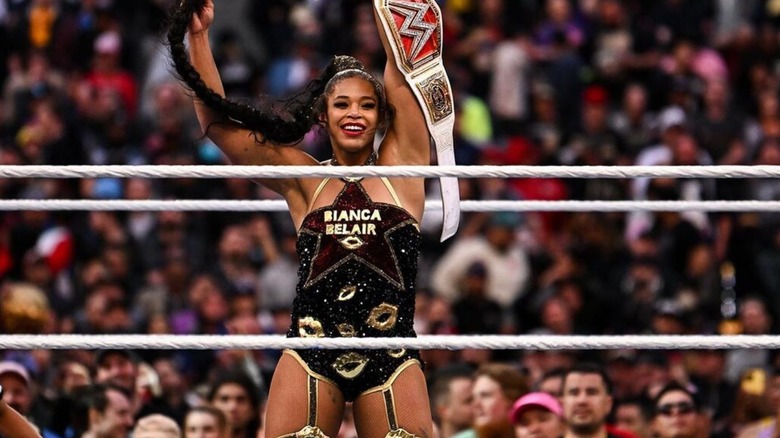Bianca Belair holds up the WWE Women's Championship, as she twirls her braid, following a victory at WrestleMania.