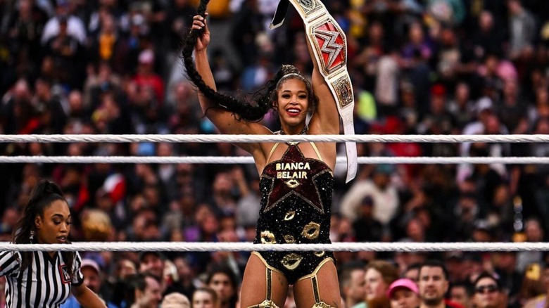 Bianca Belair holds up the WWE Women's Championship, as she twirls her braid, following a victory at WrestleMania.