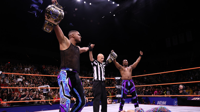 A referee holds up the hands of Isiah Kassidy and Marq Quen following their AEW World Tag Team Championship victory over the Young Bucks on an October 2024 edition of 