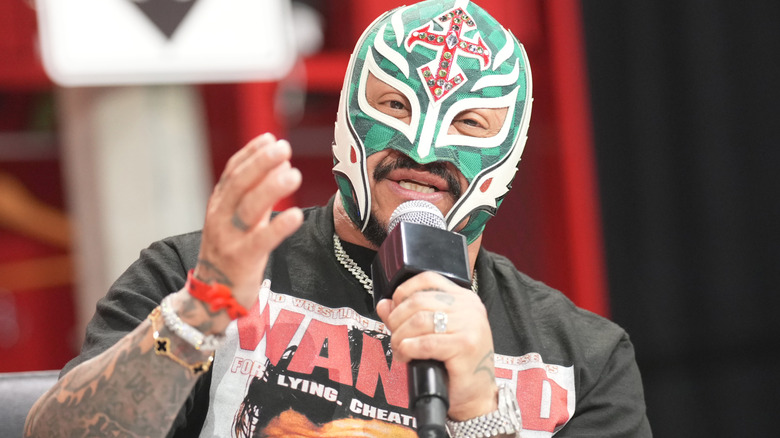 Rey Mysterio is holding a microphone