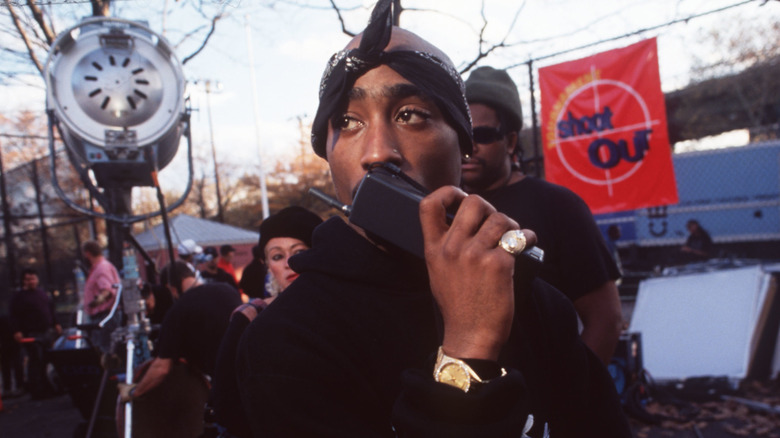 Tupac Shakur speaking into a walkie talkie outside