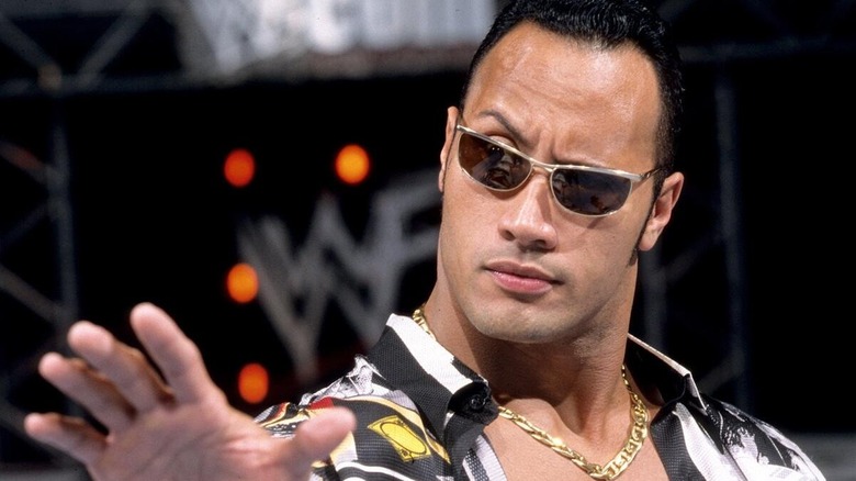 The Rock poses in the ring, eyebrow raised, as he cuts a promo in a WWF ring.