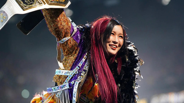 IYO SKY poses triumphantly with the WWE Women's Championship.