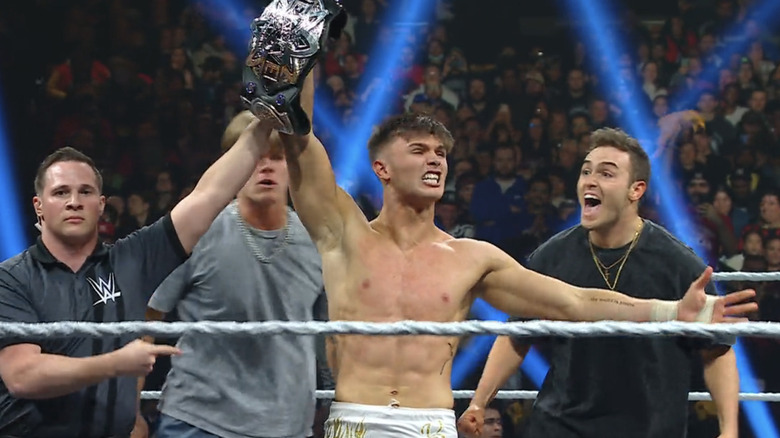 Jackson Drake bares his teeth as he hoists up the EVOLVE Championship amidst The Vanity Project.