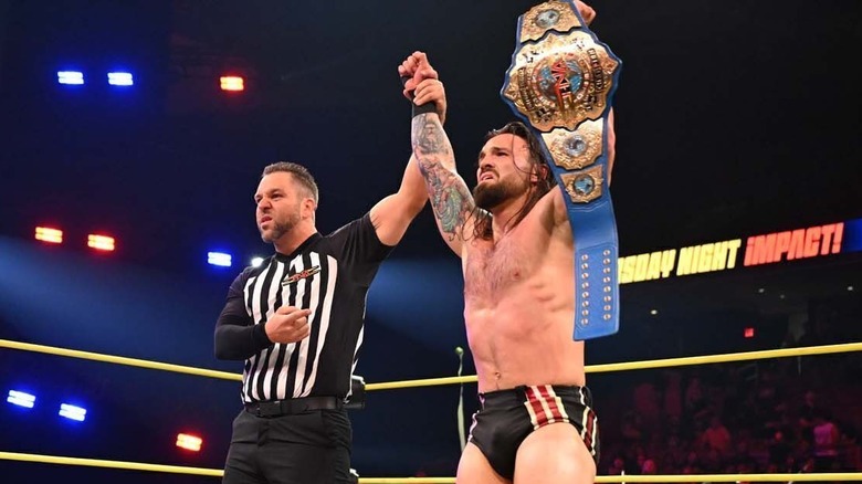 A referee holds up the arm of Jason Hotch, who holds up the TNA International Championship after a victory over Mustafa Ali, on an episode of 