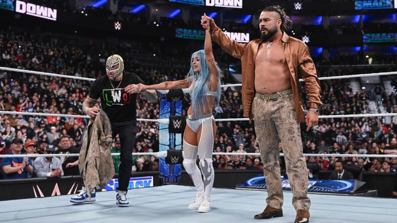 Rey Mysterio and Andrade hold up Zelina Vega's hands in victory
