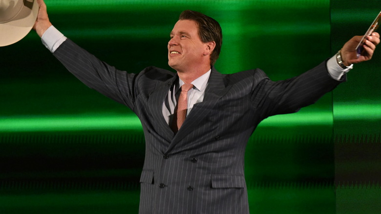 JBL smiles as he holds his signature cowboy hat and WWE speech cards during a WWE appearance.