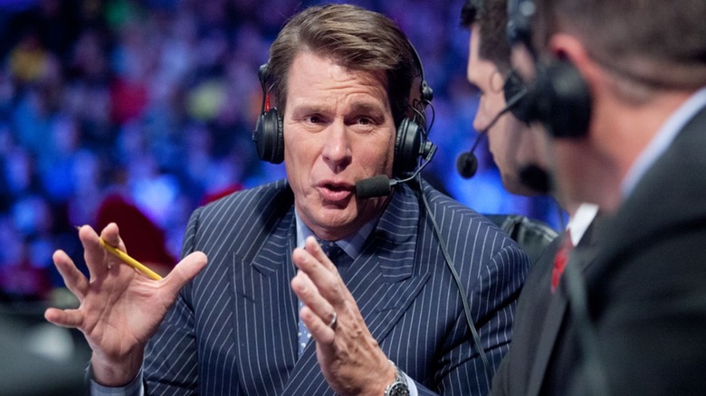 WWE Hall of Famer John Bradshaw Layfield speaks to his fellow commentators behind the desk during an episode of WWE programming.